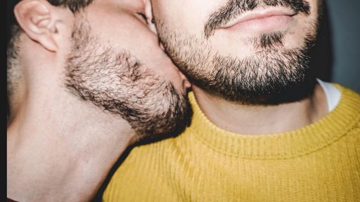Two men close together, one kissing the other’s neck